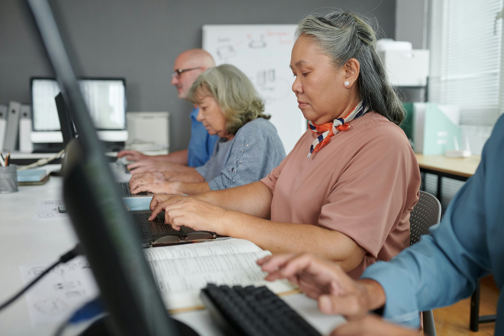 Adults working on computers in a classroom