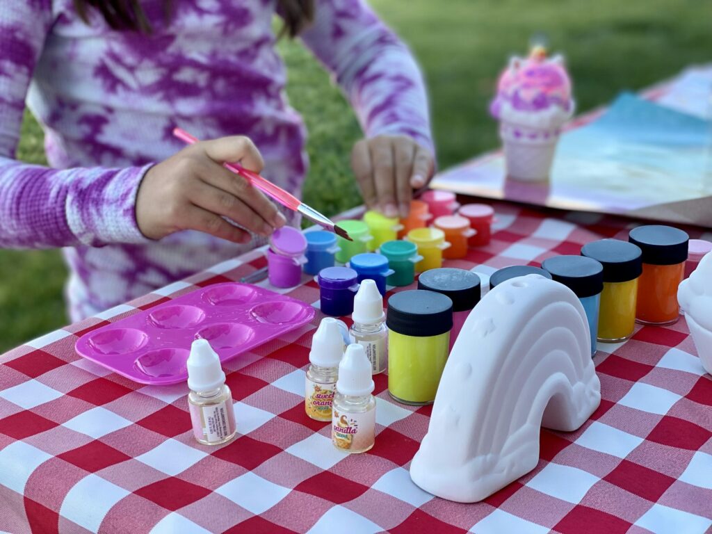 Art and Crafts. Girl painting ceramics. Colorful and fun. Crafting on a picnic table outside.