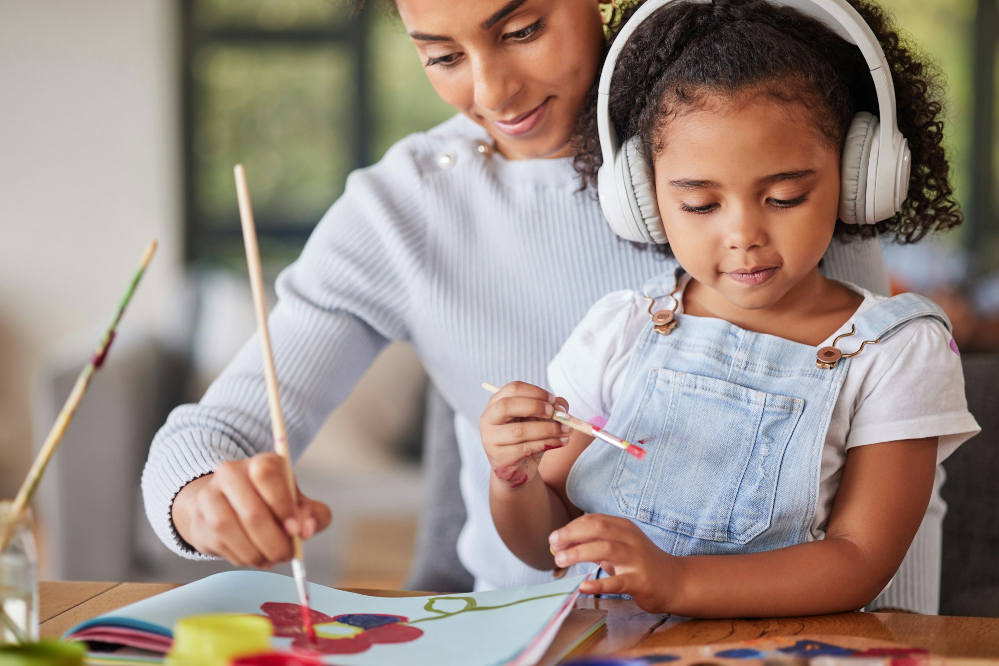 Mother, girl and bonding in painting activity with music headphones, radio or audio for autism help