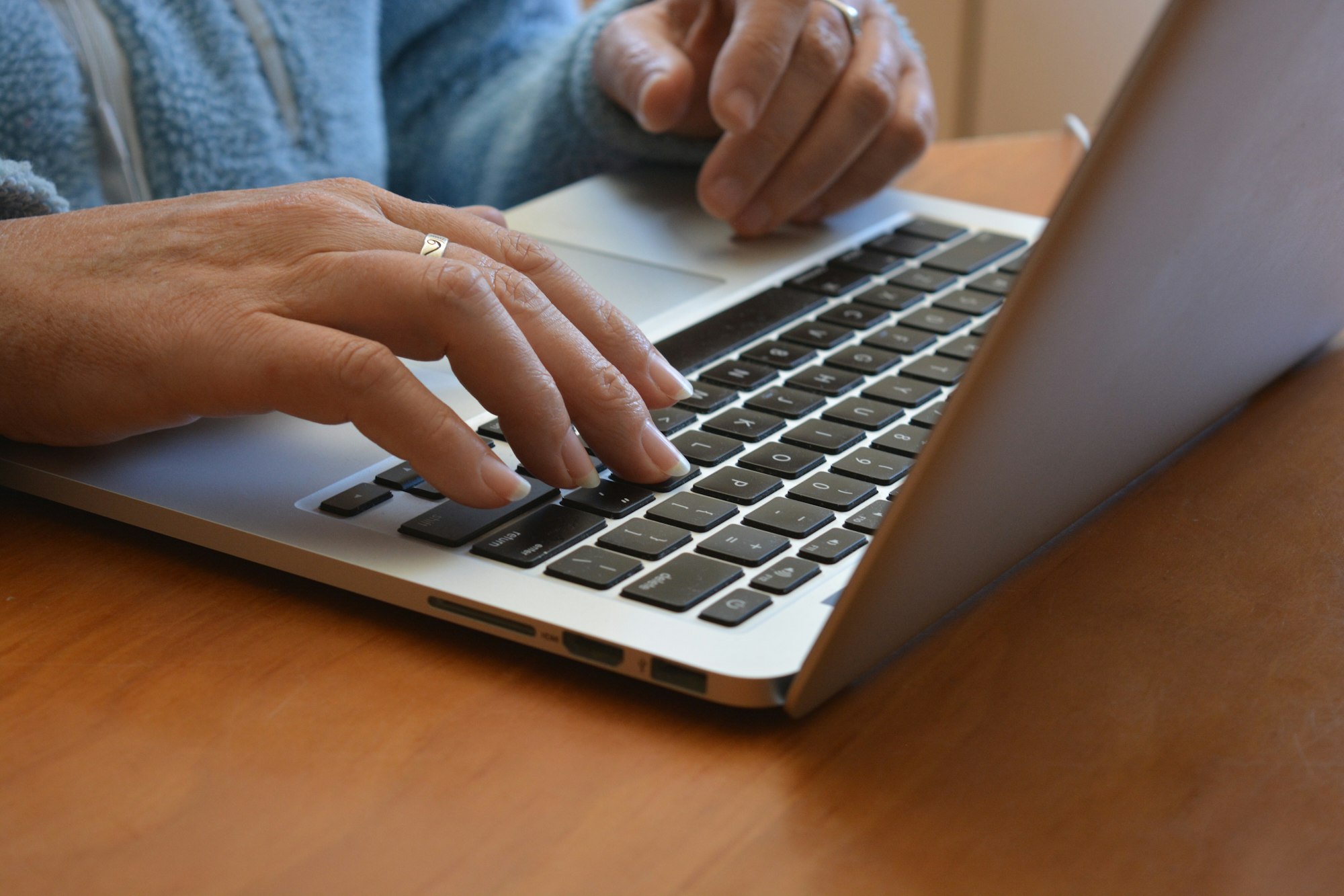 Woman using laptop, hand on keyboard, closeup