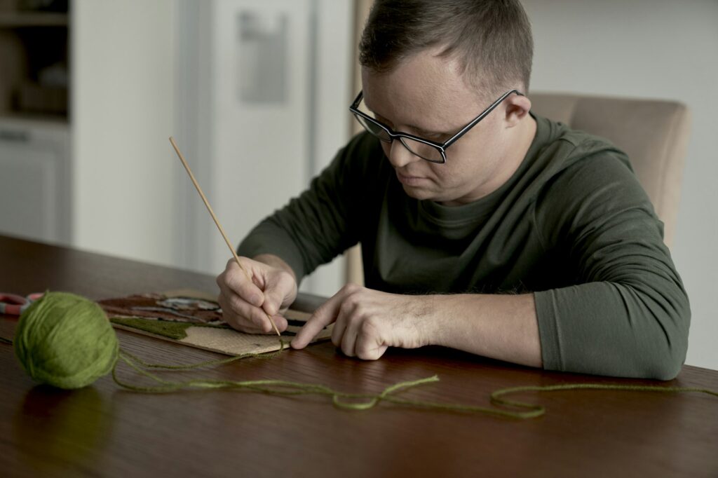 Adult caucasian man with down syndrome making a craft