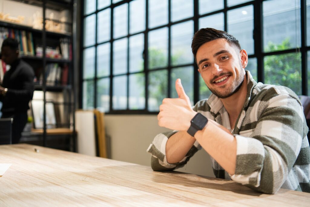 Portrait of handsome young man showing thumb up to camera.