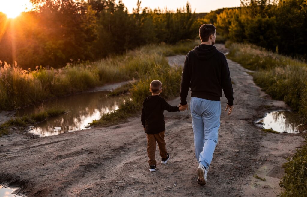 Dad and son walking on a country road at sunset