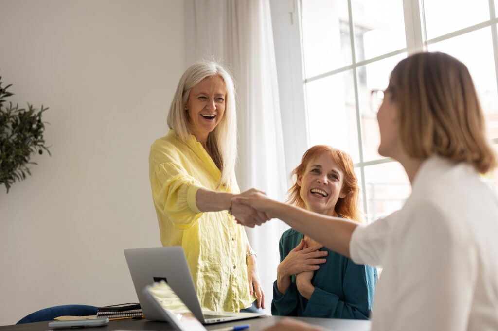 handshake mature business women - business women of different ages in the office