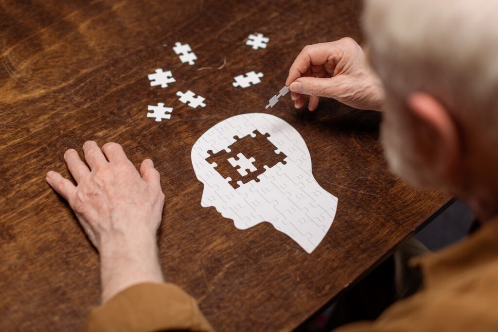 high angle view of senior man collecting jigsaw puzzle as dementia rehab