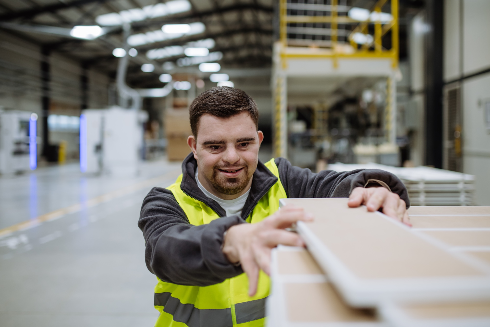 Portrait of young man with Down syndrome working in warehouse. Concept of workers with disabilities