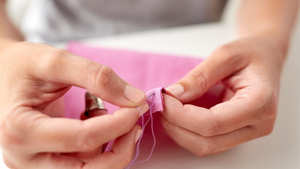 woman with needle stitching fabric pieces