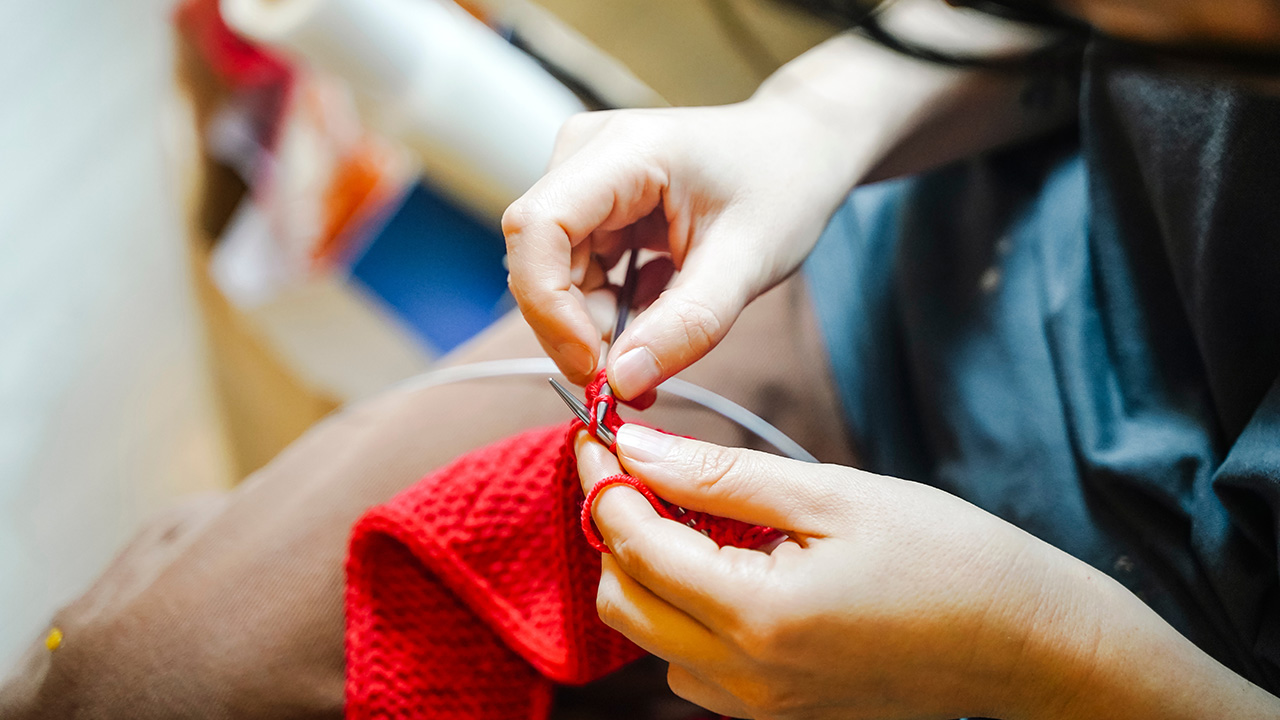 Close-up of Hands Knitting Bright Red Yarn
